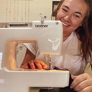 阿什利·布赫兹 smiles from behind her sewing machine.